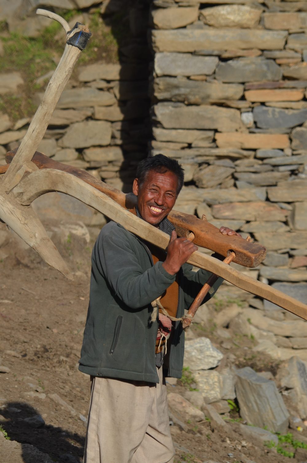Man carrying timber, traditional stone building in Pangi