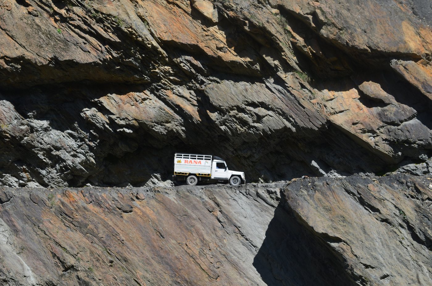 A vehicle navigating the narrow, cliff-cut road into Pangi Valley